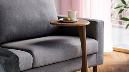 IKEA UGGLERUM Side Table in Brown in front of gray sofa with mug on top, pink sheer curtains, and timber floor