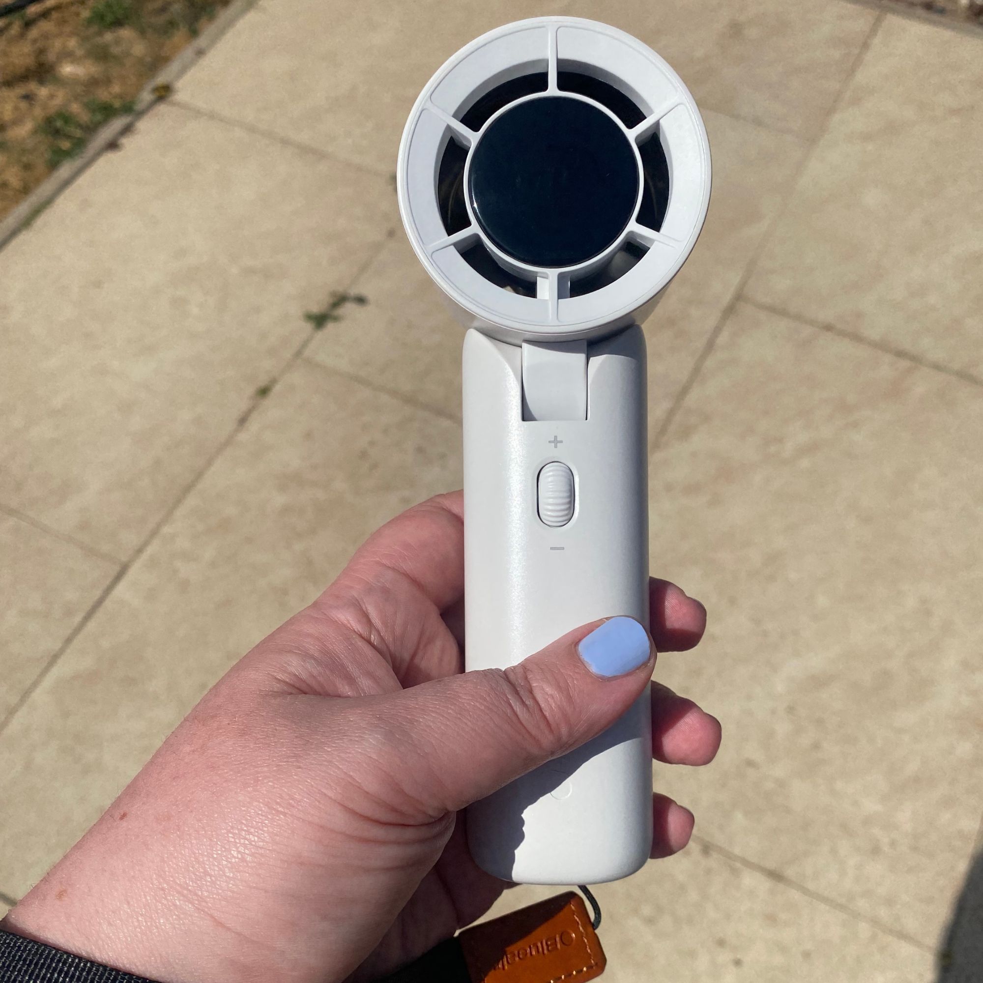 Holding the Blueair AlwaysCool Portable Handheld Fan in my garden on a hot day