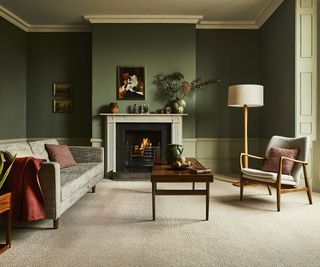 a living room with neutral carpet, green painted walls and a fireplace