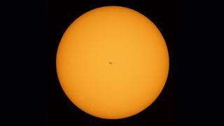 A view of the International Space Station in the center of the sun during a June 25, 2021 transit. Two astronauts, not visible here, were working outside the station at the time.