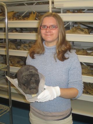 Researcher Alexandra Touzeau holding a mummy skull with its skin and hair still attached.