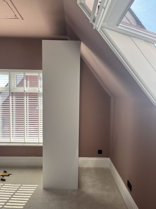 An attic with a pitched ceiling and a white pax wardrobe that doesn't maximize the space
