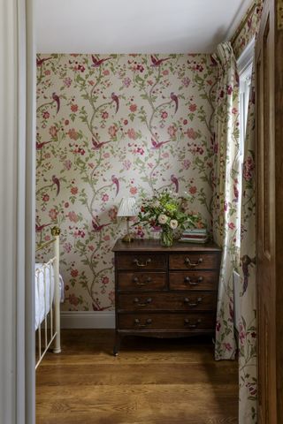 second bedroom with patterned wallpaper and antique dresser