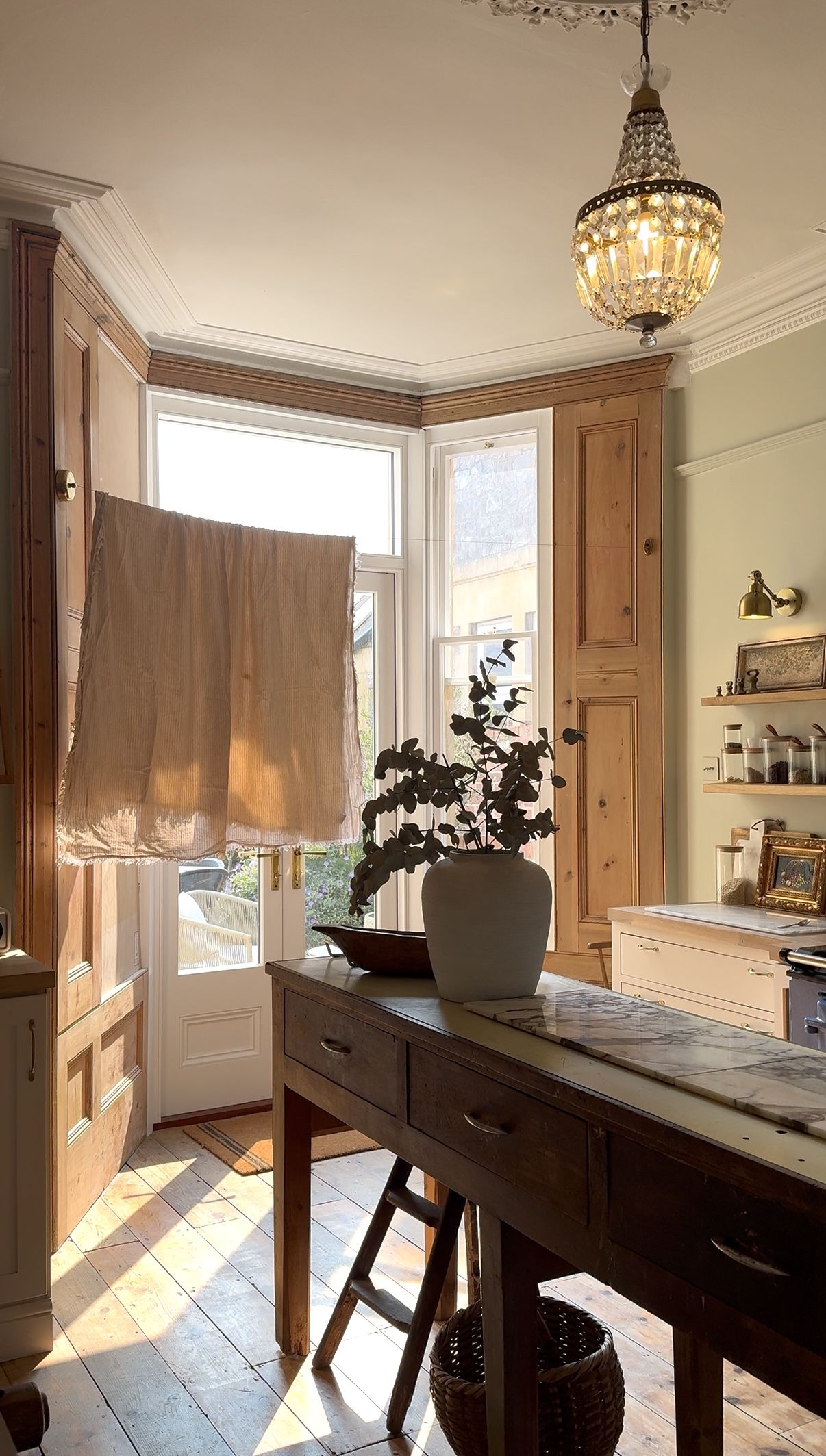 Image of a rustic-style kitchen with a large bay window that has a retractable clothesline hanging in front of it. There is a dark wooden kitchen island.