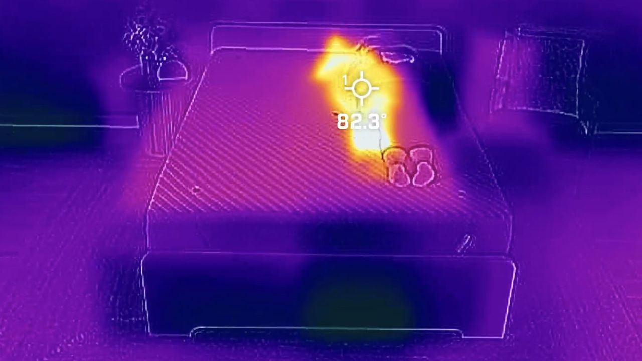 A picture of the Siena Memory Foam Mattress taken using a thermal imaging camera. This screenshot is from 9 minutes into the testing period, when our readings showed the temperature at its highest. In the image, our tester Ruth Jones lies on the right side of the mattress and she shows on the thermal imaging camera as a bright white / yellow shape. The rest of the mattress is cooler in comparison and shows up purple. A crosshair is placed in the center of the body, displaying a temperature reading of 82.3&deg;F.