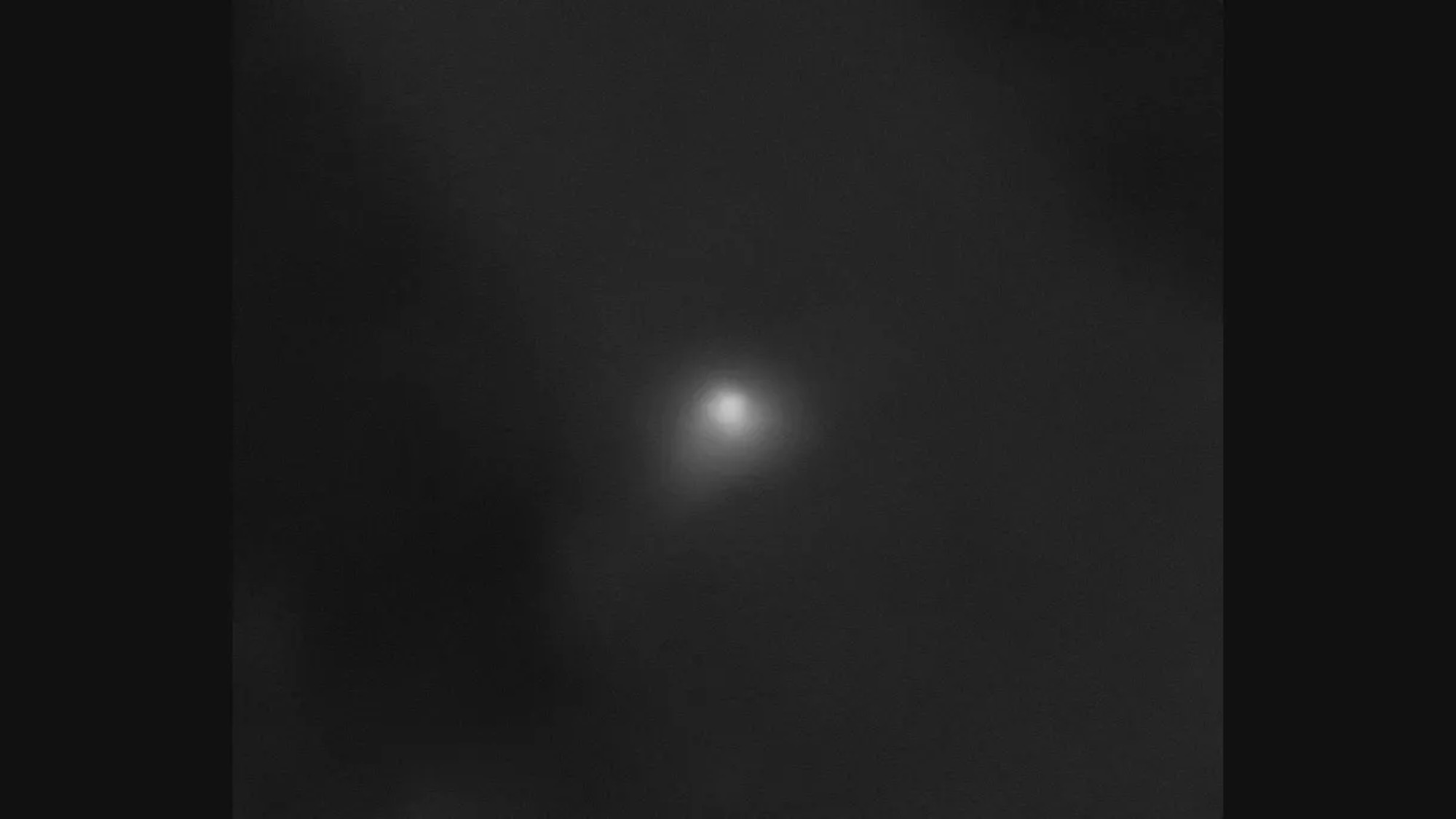 A grayscale image with a glowing ball of light in the center.