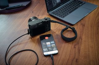 Leica Q3 connected to phone, beside laptop