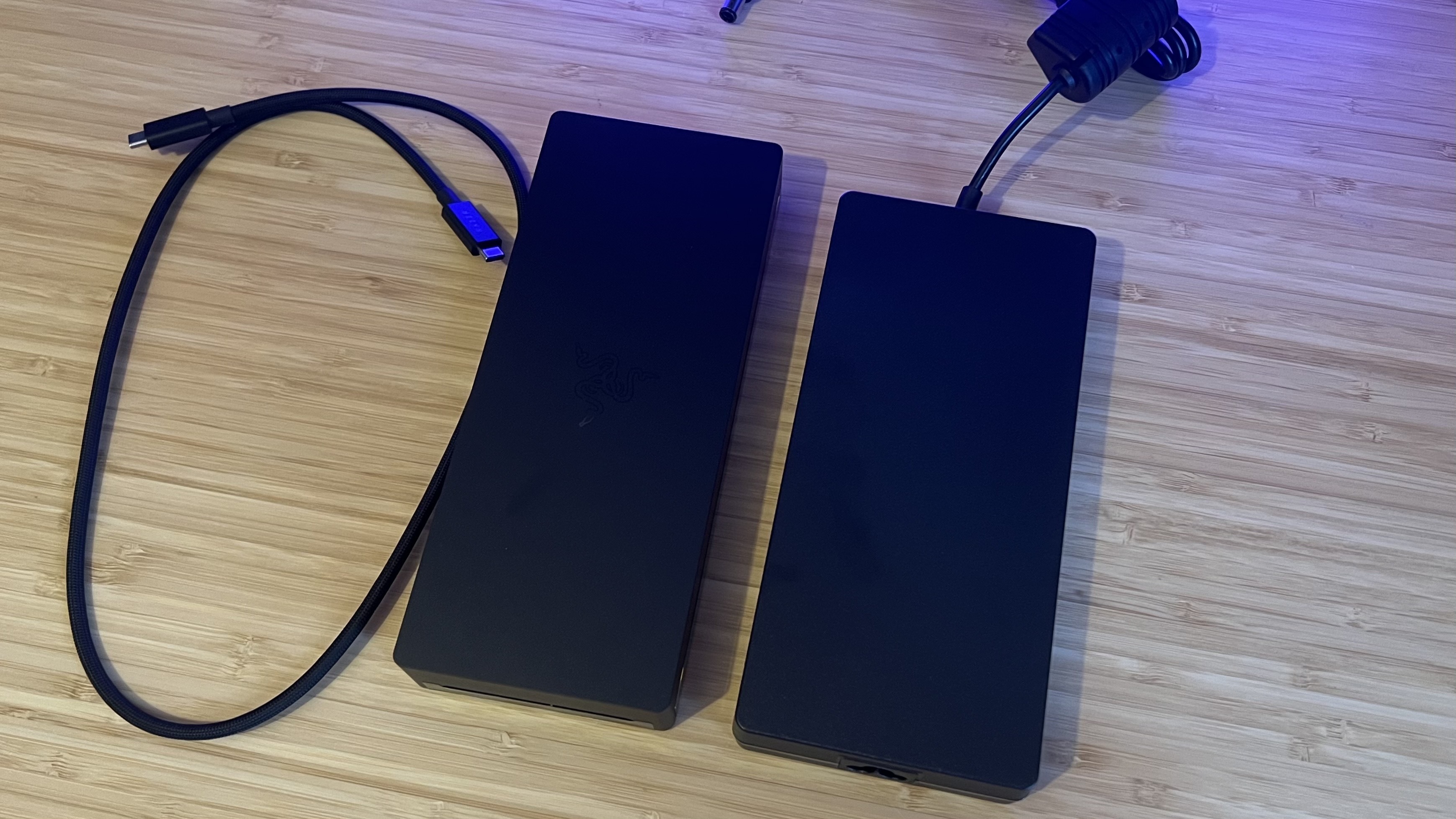 Razer Thunderbolt 5 Dock Chroma next to power brick on a wooden table