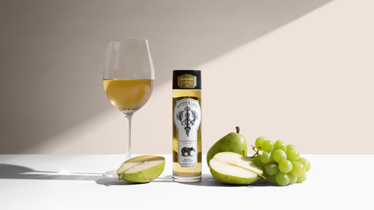 single-serve bottle of white wine on a table with grapes and pears