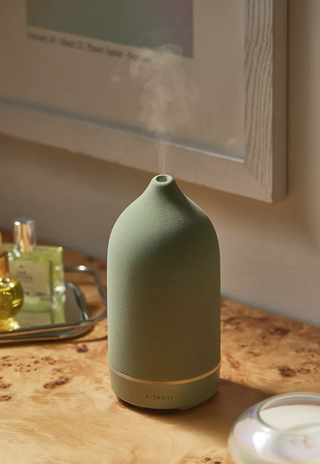 essential oil diffuser sitting on a desktop with steam coming out of the top