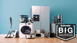 A selection of large and small kitchen appliances grouped together in front of a blue painted wall and on a wooden floor