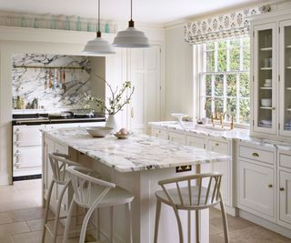 A white kitchen with uniform marble worktops