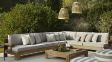 An outdoor living room with a pair of hanging woven lanterns above