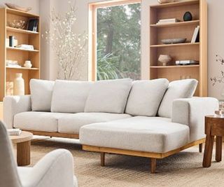 A light gray sofa in a warm brown-toned living room lined with bookshelves.