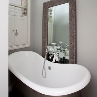 white ceramic bathtub near brown wooden framed mirror