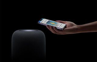 Hand holding phone near Apple HomePod second generation
