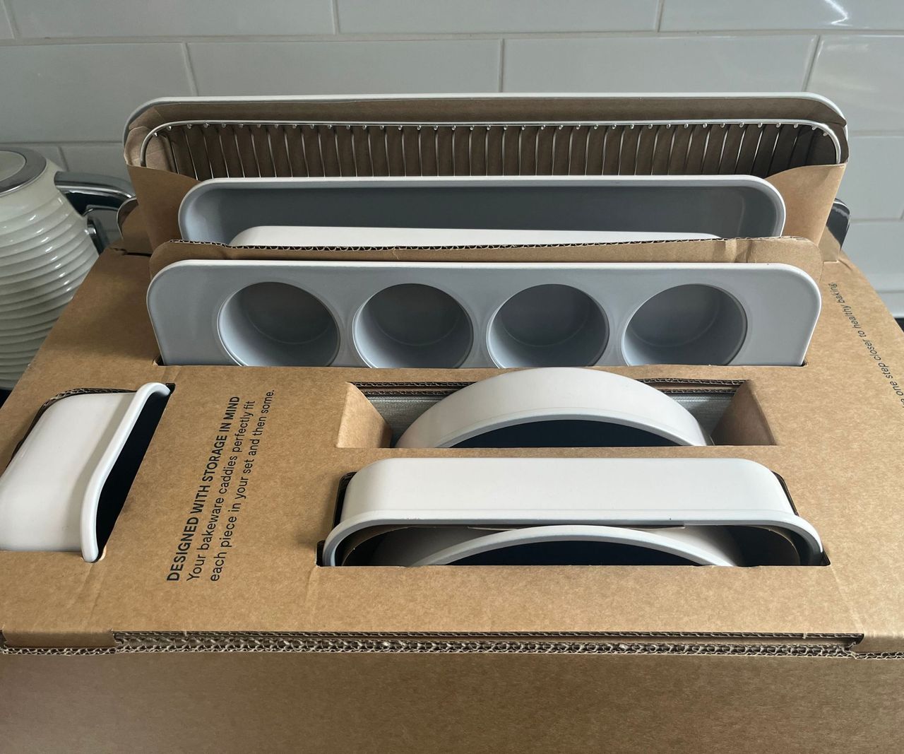 A box of Caraway bakeware on a black kitchen counter.