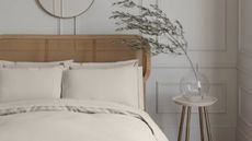 A modern, neutral, panelled bedroom wall with a rattan headboard and luxurious, cream bedding from M&S.
