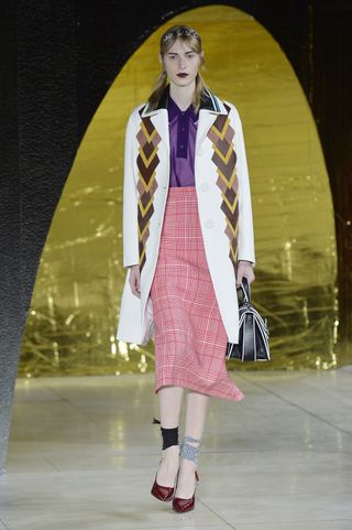 A model walks down the runway at a fashion show.