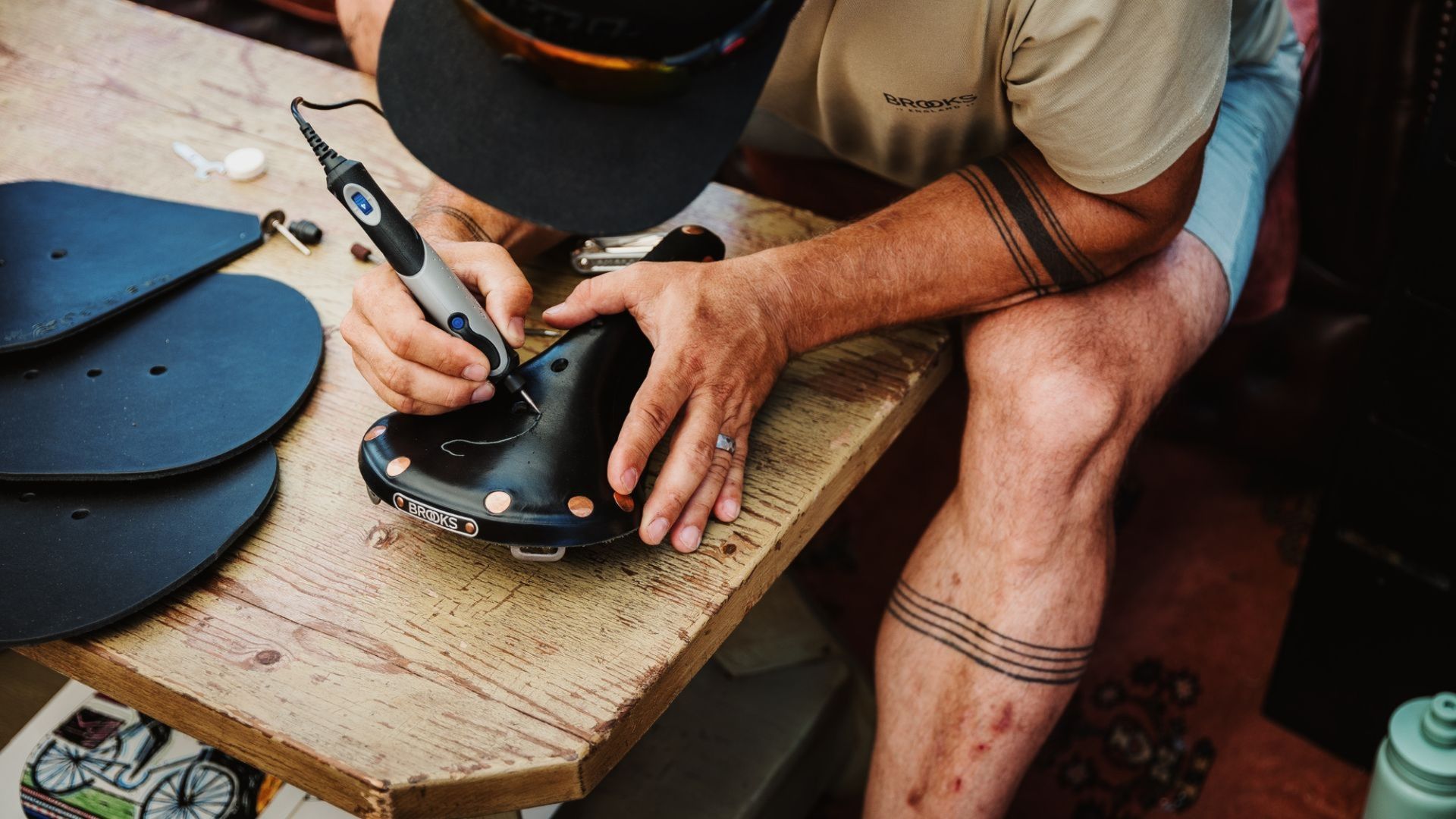 Image shows artist Jeremy Collins etching a design into a Brooks B17 saddle