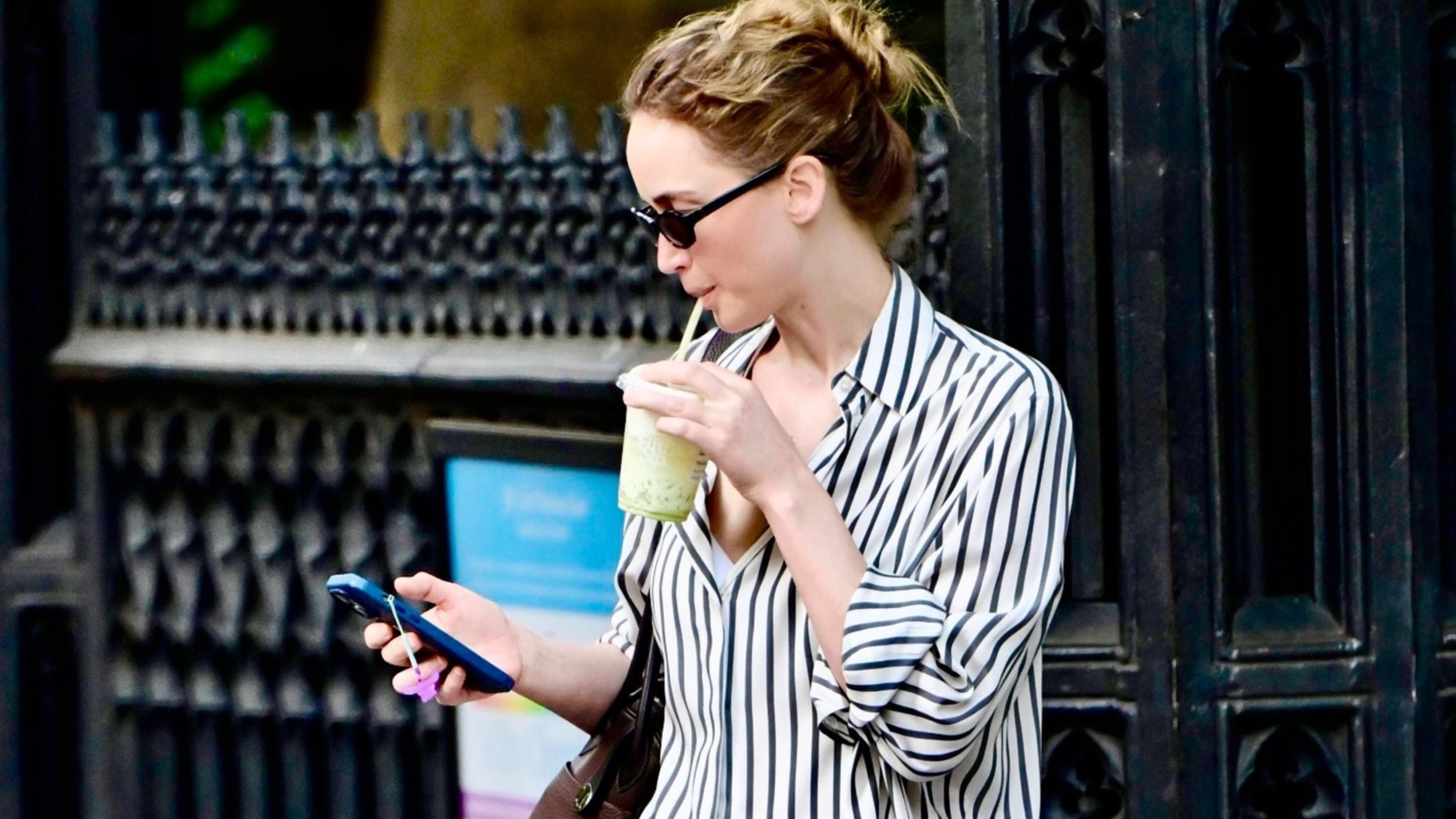 Jennifer Lawrence showcasing a stylish street style look in New York City. The actress paired wide-leg coral pants with a black and white striped shirt and The Row loafers in butter yellow.