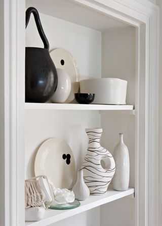 white shelving with various white, off white and black ornaments and vases