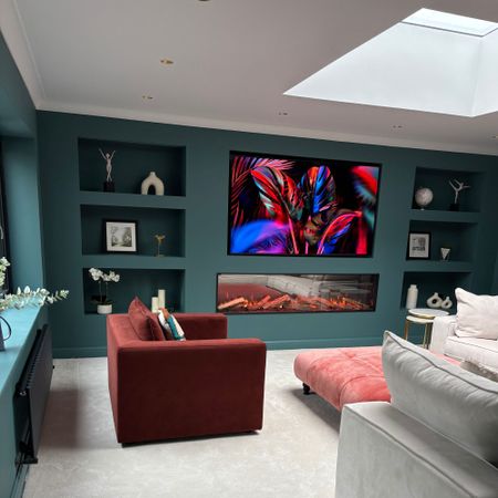 Media room with large electric fireplace, Samsung TV, large sofa, accent chair and buttoned footstool