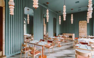 Interior of the Opasly Tom restaurant in Warsaw with green walls, tiled floors and terracotta coloured accents