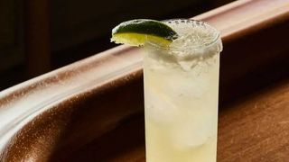 A tall glass rimmed with salt and garnished with a lime