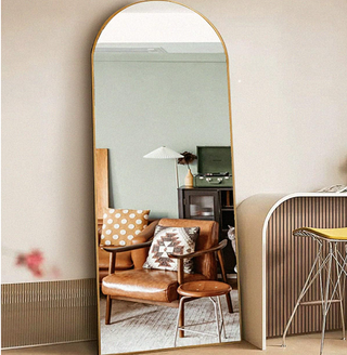 arched gold rim mirror leaning on a wall