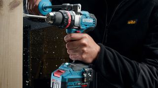 Person holding Erbauer EXT 18V Elite Combi Drill drilling into wood