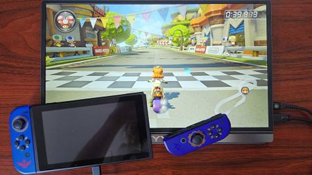 Original Nintendo Switch with Zelda Skyward Sword Joy-Con connected to KYY portable monitor with Mario Kart 8 Deluxe gameplay on screen.