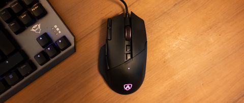 A black AOC AGM600 gaming mouse sitting on a brown wooden desk