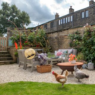 garden of a terraced cottage with gravel terrace area, furniture and chickens