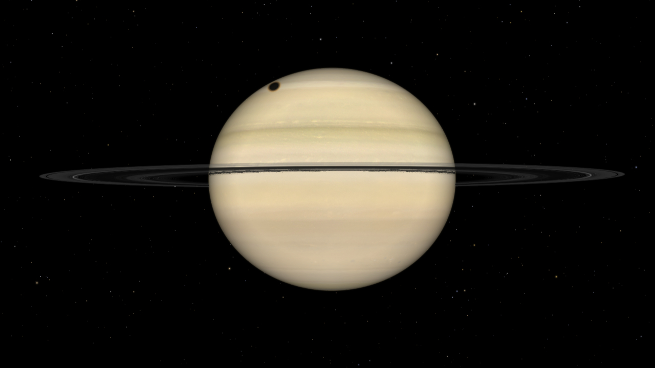 A simulation of Saturn is shown, with the dark silhouette of the large moon Titan visible as a dark circle on the upper left part of the planet&#039;s disk. Cloud bands are pictured crossing the planet&#039;s surface above and below the gas giant&#039;s ring system, which is orientated almost edge-on to the viewer.