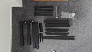 Flexispot E7 Plus standing desk legs and mechanism laid out on grey carpet