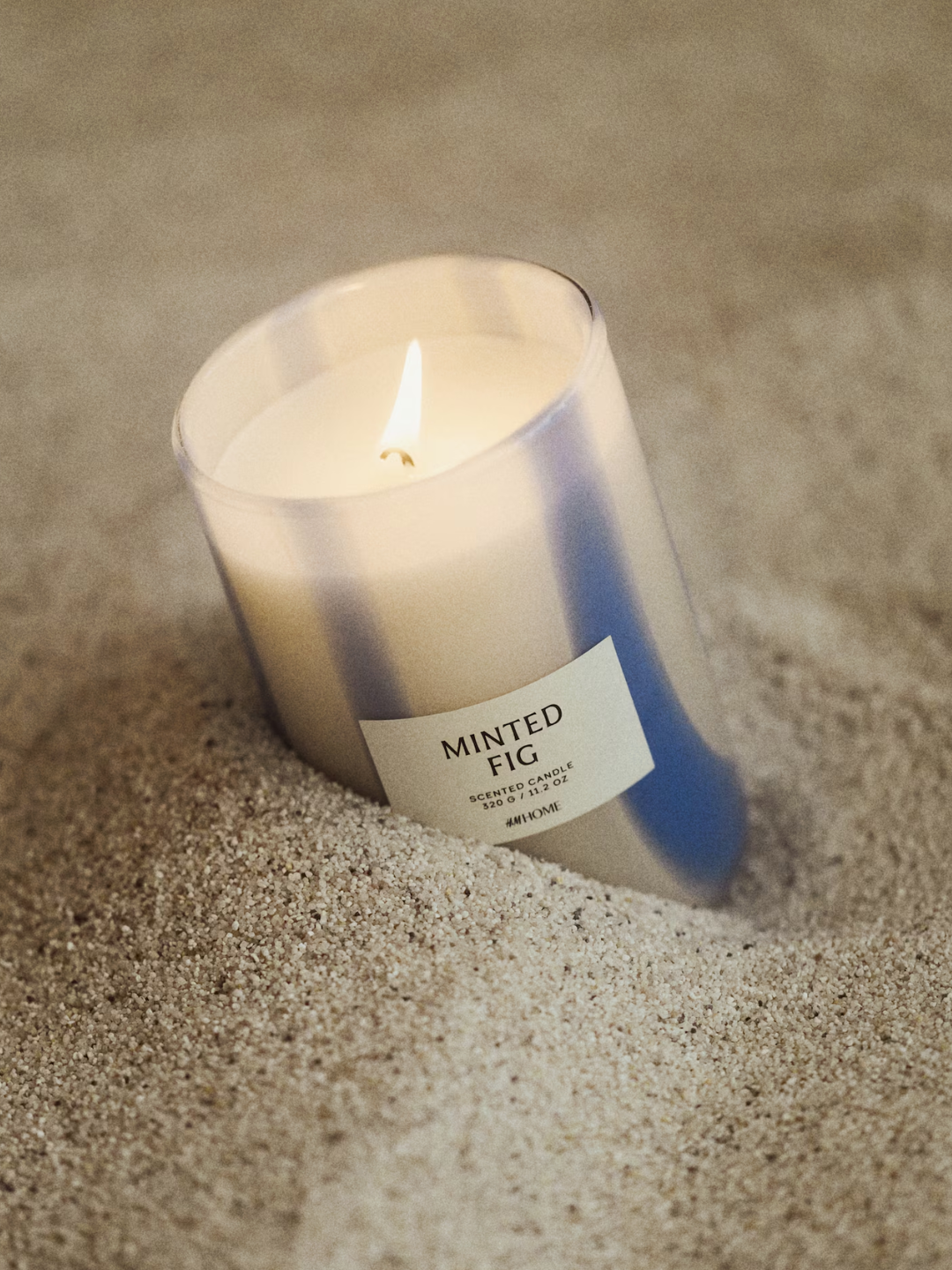 A blue and white glass minted fig scented candle from H&M in sand