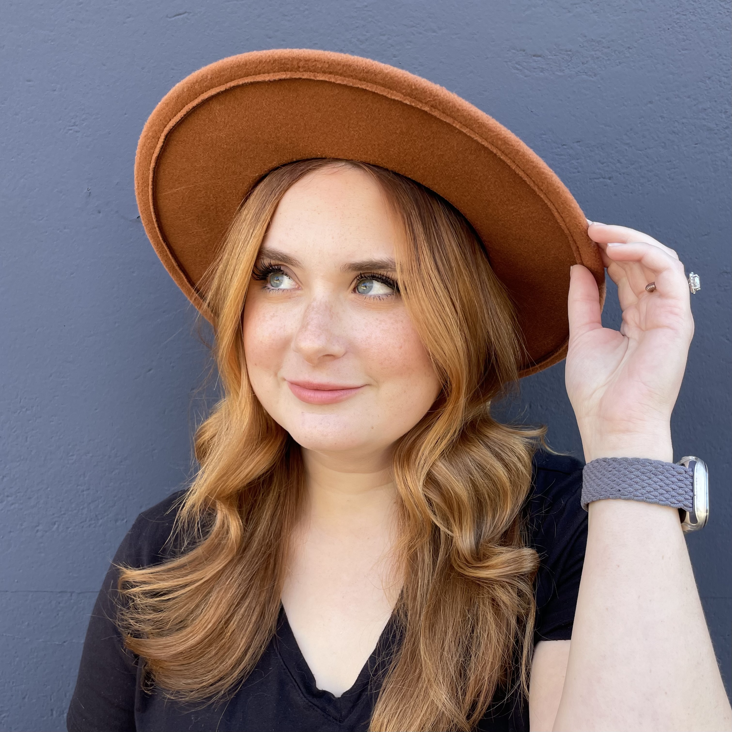 a red headed woman in a copper har and black t-shirt