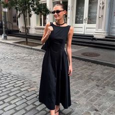 Influencer Coco Schiffer wears a black midi boatneck dress with black thong kitten heels.