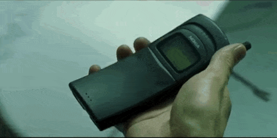 A Gif from The matrix, where Keanu Reeves holds a mobile phone, looks at it and slides out the lid by clicking a button on its side.