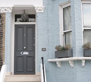house with grey wooden door blue walls and grey pipe