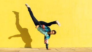 Acrobat doing movement training in front of a yellow wall. Breakdance