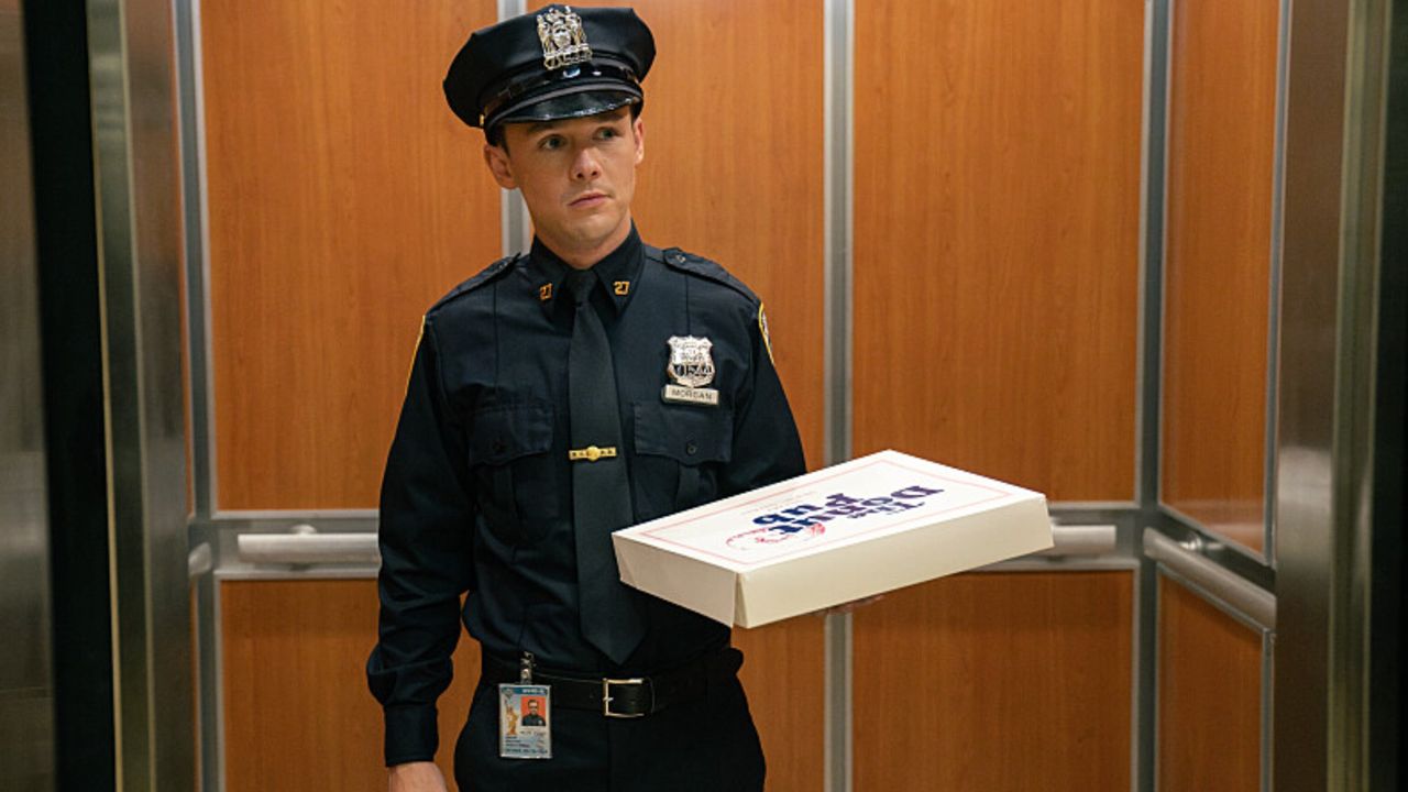 Harrison in a cop uniform with a pizza.