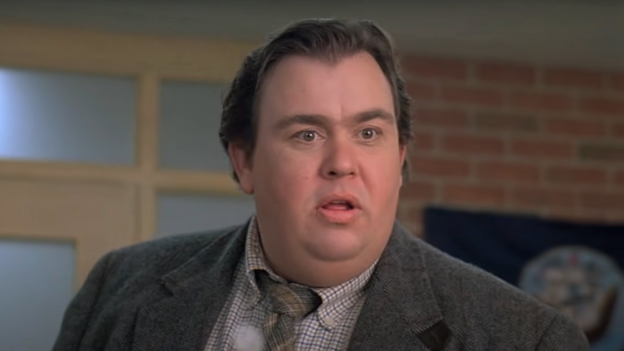 John Candy stands upset in an office in Uncle Buck.
