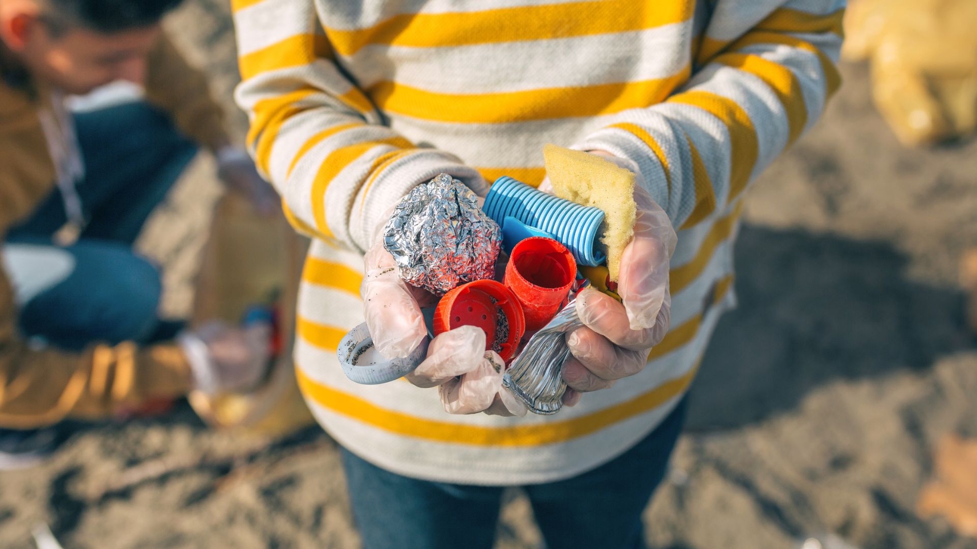 A woman showing the litter she has picked up from a beach clean