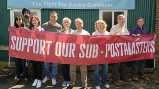The cast of "Mr. Bates vs The Post Office", including Toby Jones (centre), pose with a banner reading "support our sub-postmasters"