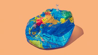 An inflatable world globe lies crumpled, with half the air having leaked out.