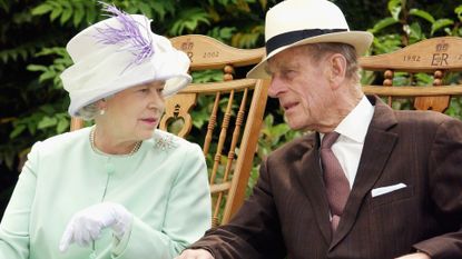 Queen and Prince Philip, the Duke of Edinburgh chat while watching a musical performance in the Abbey Gardens during her Golden Jubilee visit to Suffolk in this July 18, 2002
