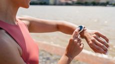 A close-up picture of a woman checking her fitness watch while exercising outdoors