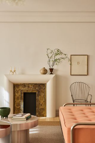 A bulbous white plaster fireplace surround borders a bronze fireplace design.